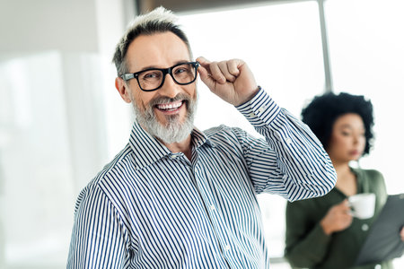 Confident business professionals in a well-lit office space emphasizing teamwork and success during collaborationの写真素材