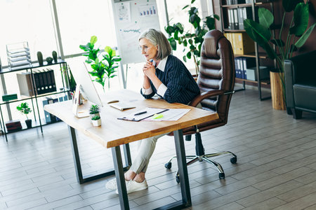 Experienced businesswoman working in a professional office setting surrounded by modern interior design and focused atmosphereの写真素材