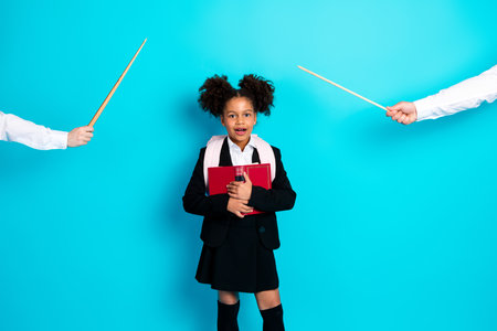 Portrait of a stylish schoolgirl holding a red book on a turquoise background with two guiding hands...