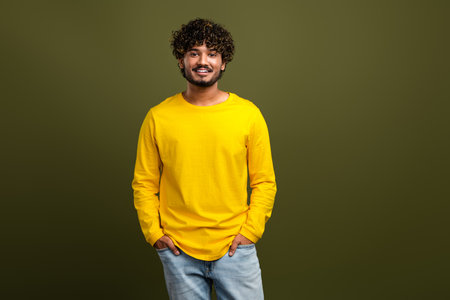 Portrait of a young man wearing a vibrant yellow shirt against a stylish khaki background,...