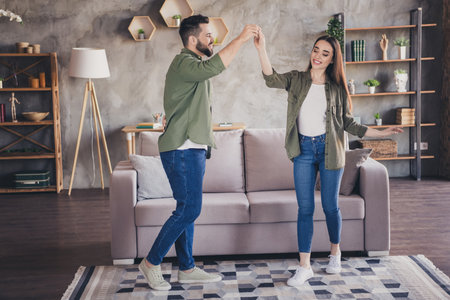Photo of positive good mood man woman dressed khaki shirts dancing smiling indoors house apartment roomの写真素材