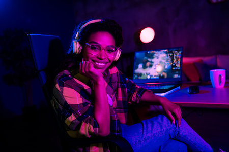 Portrait of young girl sit chair desktop play gaming laptop neon light dark room evening flat...