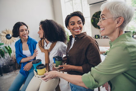 Photo of corporate four colleagues women feminists share coffee tea break spend time together cafe meeting coworking successful officeの写真素材