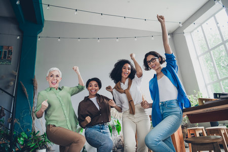 Photo of successful corporate women raise fists accomplish modern interior office business center indoorsの写真素材