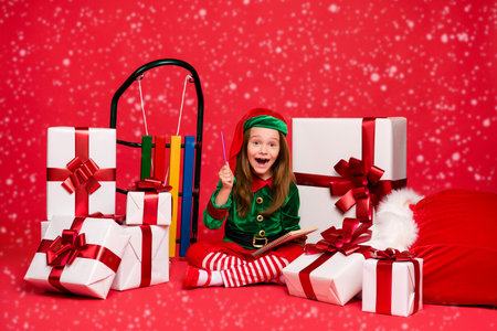 Nice attractive cheerful cheery excited funny funky small little pre-teen elf creating winter holly...