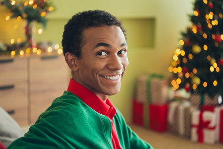 Photo of nice young man toothy smile wear green cardigan christmas festive time apartment indoors