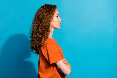 Profile side photo of focused girl look empty space with crossed arms isolated blue color background