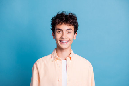 Young man in stylish casual shirt smiling confidently against a blue background showcasing youthful...