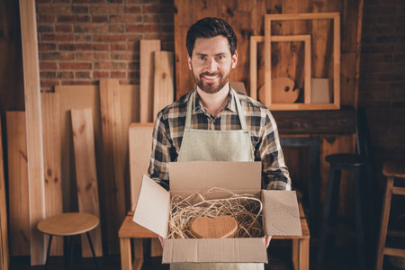 Photo of workman hold show carton box with wooden heart in garageの写真素材