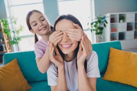 Photo of happy family lovely adorable mommy with daughter playing game indoors cozy living roomの写真素材