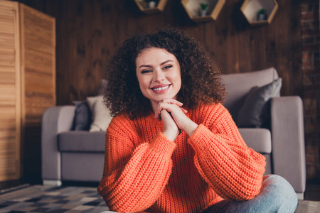 Photo of pretty young woman toothy smile good mood wear orange pullover loft interior apartment indoorsの写真素材