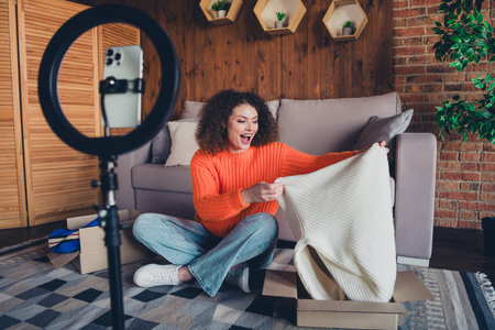 Full length portrait of nice young girl hold sweater phone holder record video modern loft interior flat indoorsの写真素材