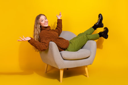 Full body profile portrait of nice young girl sit chair isolated on yellow color backgroundの写真素材