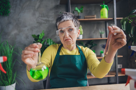 Photo of nice elderly lady confused create fertilizer wear green apron enjoying gardering indoors home business workplaceの写真素材