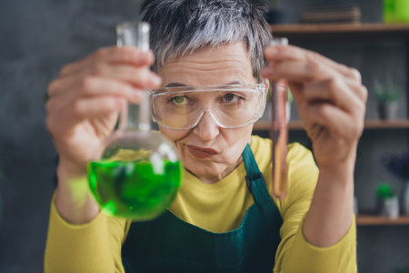 Photo of pensioner lady florist skeptical create fertilizer wear green apron working flower shop studio small businessの写真素材
