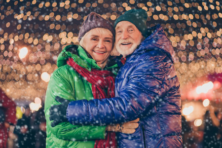 Photo of dream two people old man woman couple enjoy x-mas christmas advent eve time date hug embrace under evening illumination outsideの写真素材