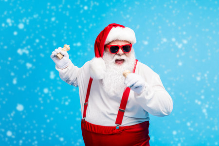 Fat cool crazy hipster santa claus sing song pepper salt pot x-mas christmas dinner feast prepare wear suspenders overall sunglass white shirt headwear isolated blue color backgroundの写真素材