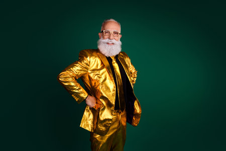 Elegant senior man in a glowing golden suit on green background celebrating eventの写真素材