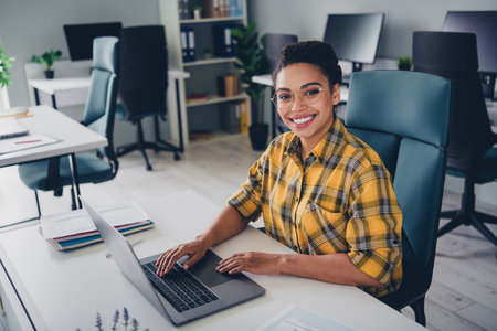 Photo of pretty young girl working netbook wear yellow plaid shirt coworking successful nice light officeの写真素材
