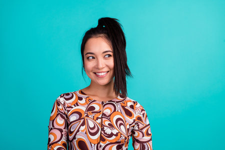 Photo portrait of pretty young girl look empty space wear stylish colorful clothes isolated on cyan color backgroundの写真素材