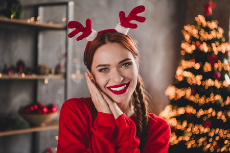 Photo of pretty young girl toothy smile reindeer horns wear sweater christmas festive holiday time apartment indoorsの写真素材