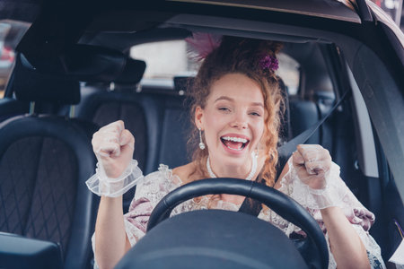 Joyful young woman dressed in vintage style driving car with a big smile and enthusiasm