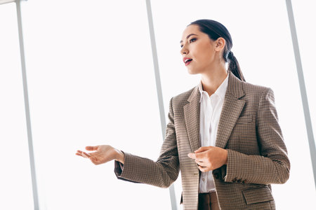 Confident professional woman explaining business concepts in a modern corporate office environmentの写真素材