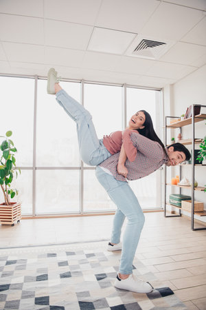 Playful couple enjoying time together in a bright apartment living room, expressing love and happiness during a sunny day indoorsの写真素材
