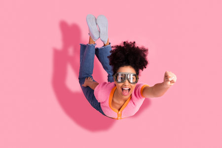 Excited young woman in fashionable pink attire posing playfully while expressing joy and confidence...