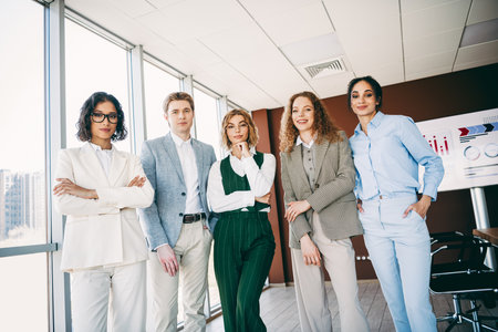 Group of confident business professionals in a modern office setting exuding collaboration,...