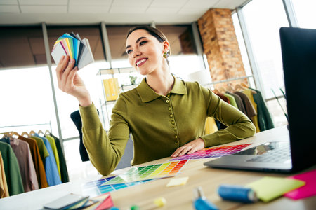Professional designer in modern atelier reviewing color palette for fashion concept creation in collaborative workspaceの写真素材