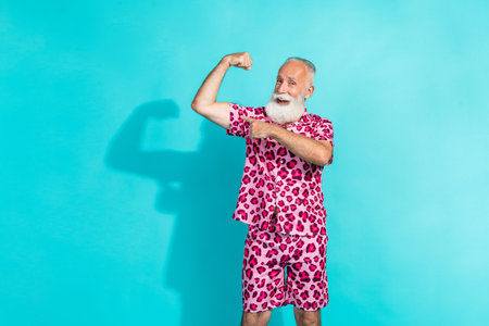 Photo of funny aged man point finger biceps wear leopard print outfit isolated on teal color backgroundの写真素材