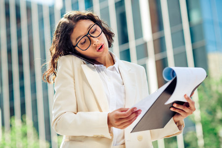 Confident Businesswoman Reviewing Documents Outdoors in Urban Settingの写真素材