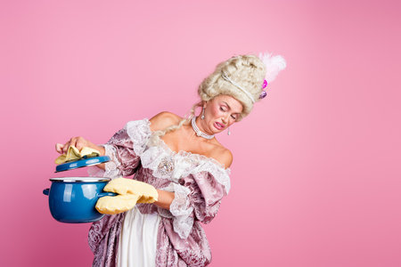 Elegant young woman in a historical costume holding a pot, with a humorous expression against a vibrant pink background.の写真素材