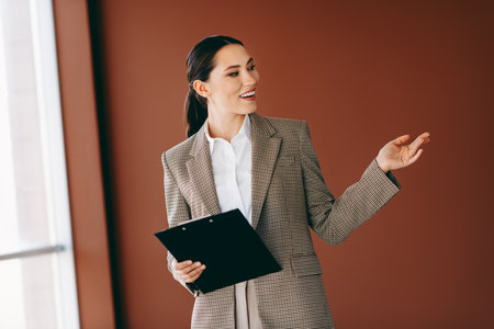Confident businesswoman presenting in office, showcasing skills and professionalism in a stylish indoor settingの写真素材