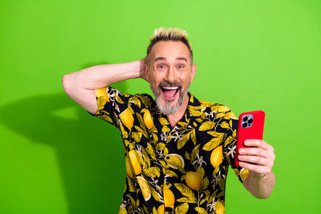Charismatic middle aged man posing joyfully with a vibrant lemon pattern shirt holding a red...
