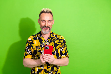Charismatic man in vibrant summer attire holding a smartphone, set against a vibrant green...