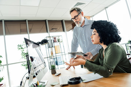 Professional team collaborating in a modern office space on a project discussion with technology and teamworkの写真素材