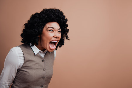 Angry Businesswoman Expressing Emotion Against Beige Background in Stylish Formal Attireの写真素材