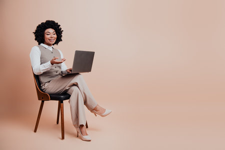 Professional businesswoman presenting ideas during an online conference in stylish attire on a beige backgroundの写真素材