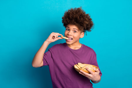 Young boy enjoys cookies in casual setting against blue background, expressing happiness and leisure.の写真素材
