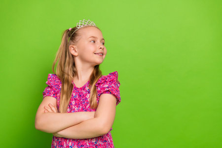 Charming Young Girl Smiling Confidently Against Green Background in Casual Dress Reflecting Joy and Stylish Personalityの写真素材