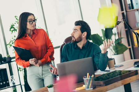Professional coworkers discussing strategy in a modern office setting surrounded by plants and technology, collaborating effectivelyの写真素材