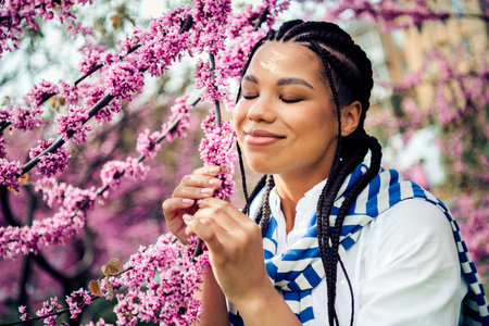 Young woman enjoying spring blossoms outdoors in a city park during a bright day