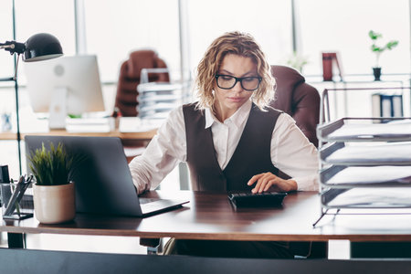 Confident female professional working in a stylish office, conducting corporate tasks with focus and dedicationの写真素材