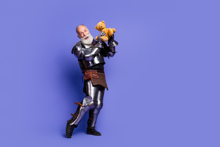 Armored knight holding a teddy bear expressing a humorous and lighthearted contrast against the bold medieval armor and vivid background.の写真素材