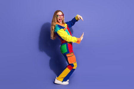 Young woman in vibrant colorful outfit showing cheerful gesture against violet background, celebrating diversity, styleの写真素材