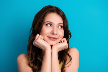 Young attractive woman posing with charming expression against vibrant blue background