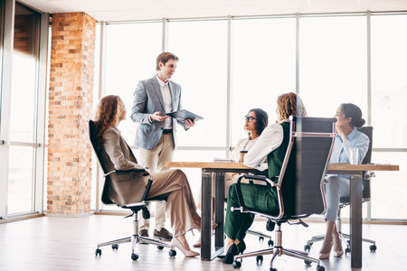 Group of business professionals collaborating during an office meeting with a focus on teamwork and...