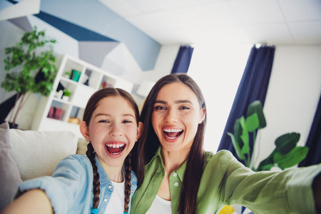 Happy mother and daughter spending quality time together at home, sharing laughter and a joyful moment in a comfortable settingの写真素材